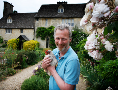 Colin holding a chicken in front of manor house