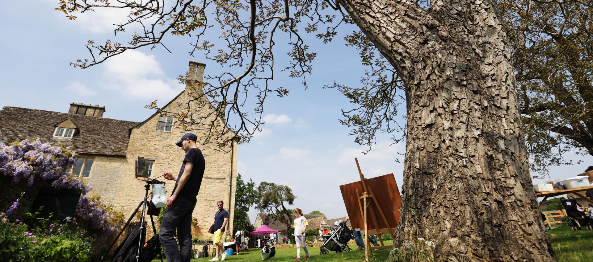 Summer scene outdoors at Cogges with families and artist