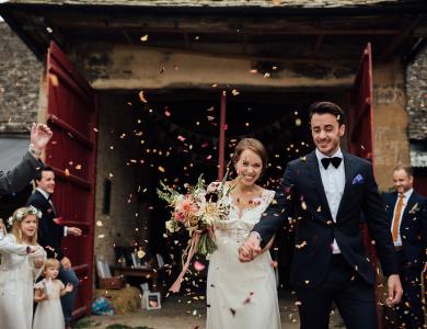 wedding couple in front of barn with confetti