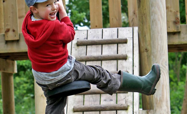 young boy swings on zip wire play equipment 